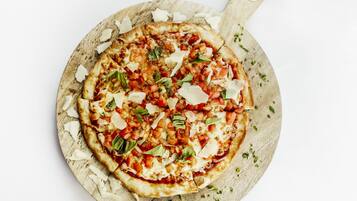 Une pizza servie sur une planche en bois munie d’une anse.