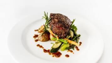A steak with vegetables and sauce on a plate.