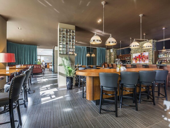 A bar area with a wooden counter, black bar stools, and pendant lighting. - Novotel Montreal Aeroport (Montreal)
