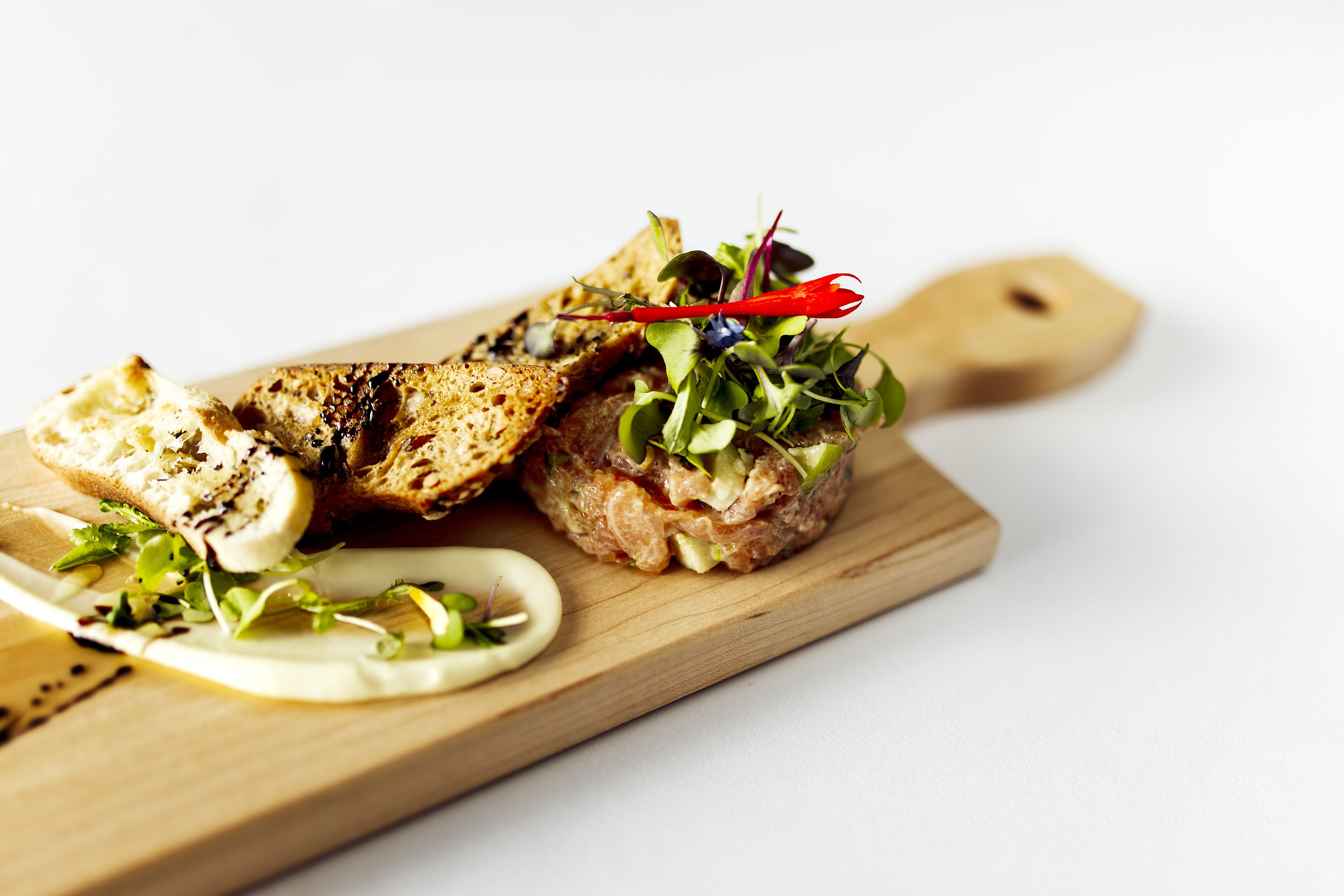 A sandwich on a wooden board with a knife.