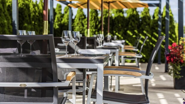Outdoor tables with yellow umbrellas, metal chairs, and glassware. - Novotel Montreal Aeroport (Montreal)
