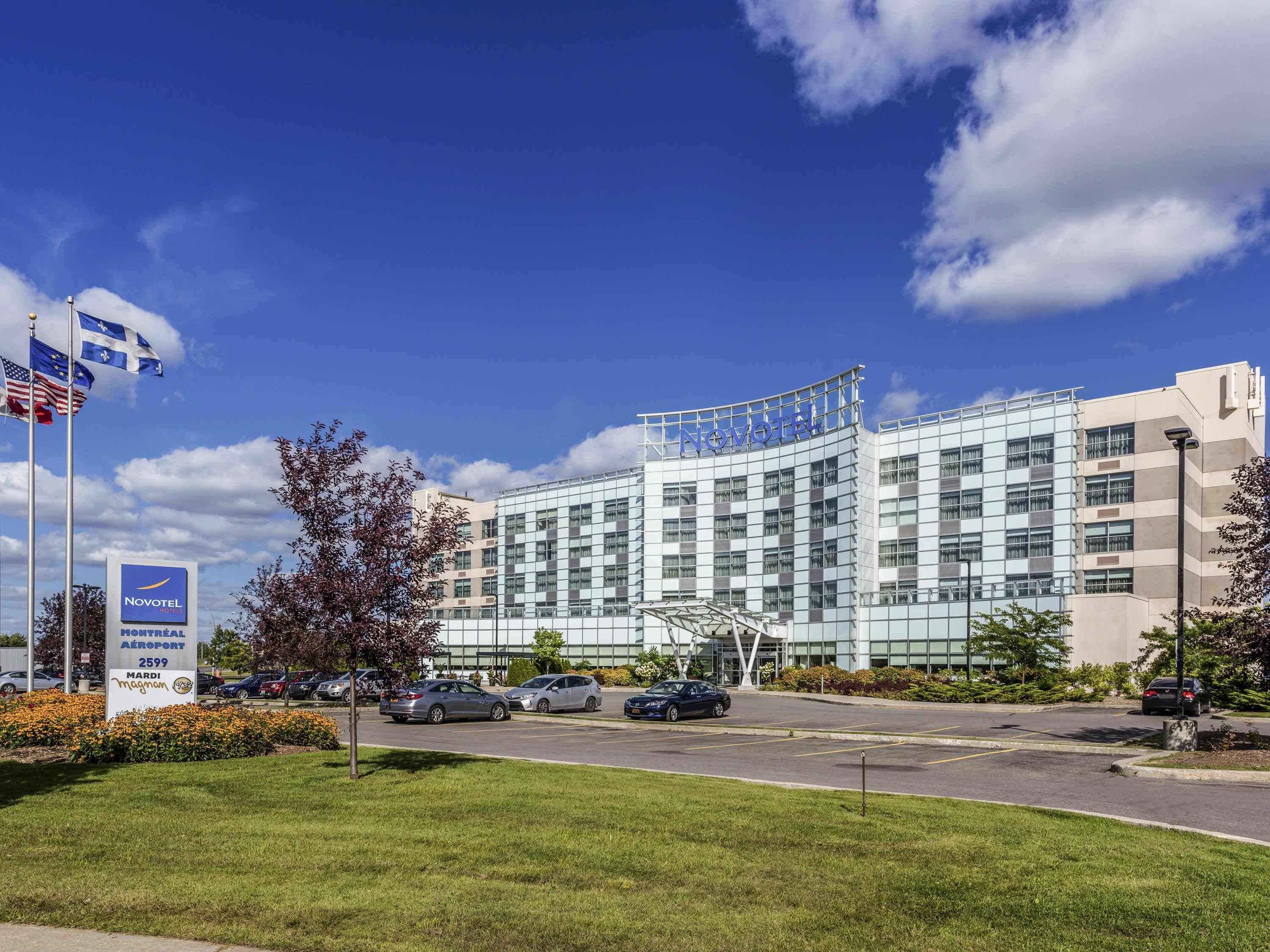 Ein Novotel Hotel mit moderner Glasfassade, einem Parkplatz und einem Schild, das den Standort Flughafen Montreal angibt.