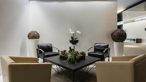 A conference room with a table, two chairs, potted plants, and a bench in a modern interior. - Novotel Montreal Aeroport (Montreal)