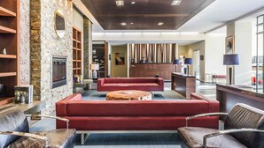A lobby with a stone wall, a fireplace, red sofas, and a reception desk. - Novotel Montreal Aeroport (Montreal)
