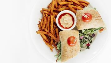 En tallerken med pommes frites, en sandwich og en lille skål med sauce.