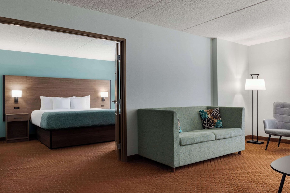 Une chambre d’hôtel avec un lit, un canapé, une chaise et une lampe.