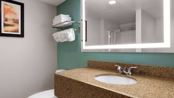 Een badkamer met een wastafel met granieten blad, een grote spiegel en een toilet.