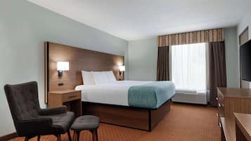 A hotel room with a bed, a chair, a desk, a TV, and a window with curtains.