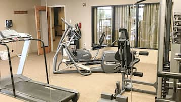 A fitness center with cardio machines, weight training equipment, and a mirrored wall.