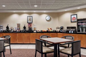 Un vestíbulo de hotel con mostrador de recepción, un reloj y una máquina de café.