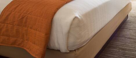 A hotel room with a large bed, two bedside lamps, a chair, and a window with curtains.