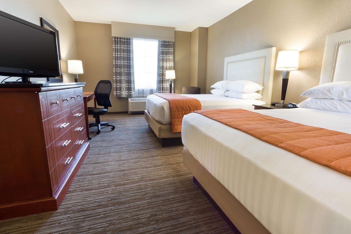 A hotel room with two beds, a TV, a desk, and a chair.