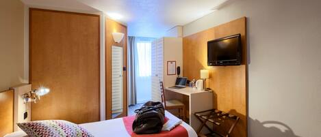 A hotel room with two beds, a desk, a TV, and a wardrobe.