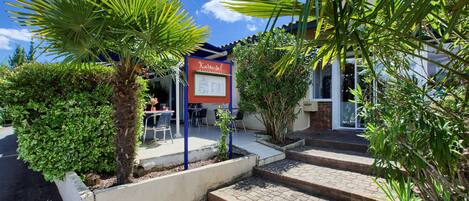 Un patio con una palmera, un cartel y escalones que llevan a un edificio.