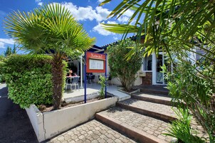 Un patio con una palmera, un cartel y escalones que llevan a un edificio.