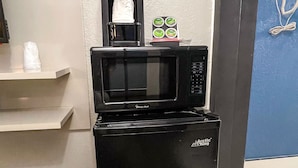 A compact kitchen area with a black refrigerator, a microwave, and a coffee maker.