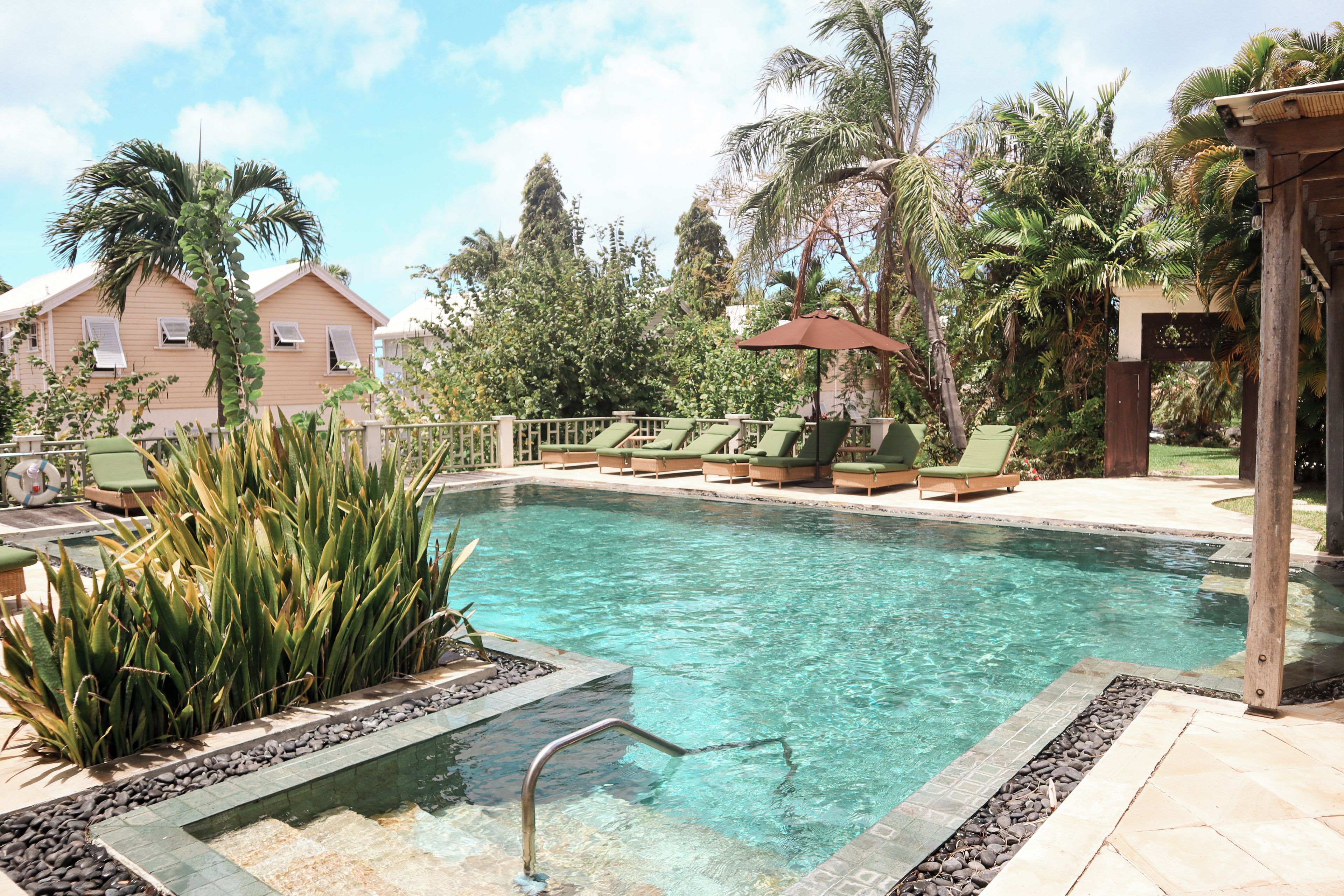 Una piscina con sillas de descanso y una pérgola.