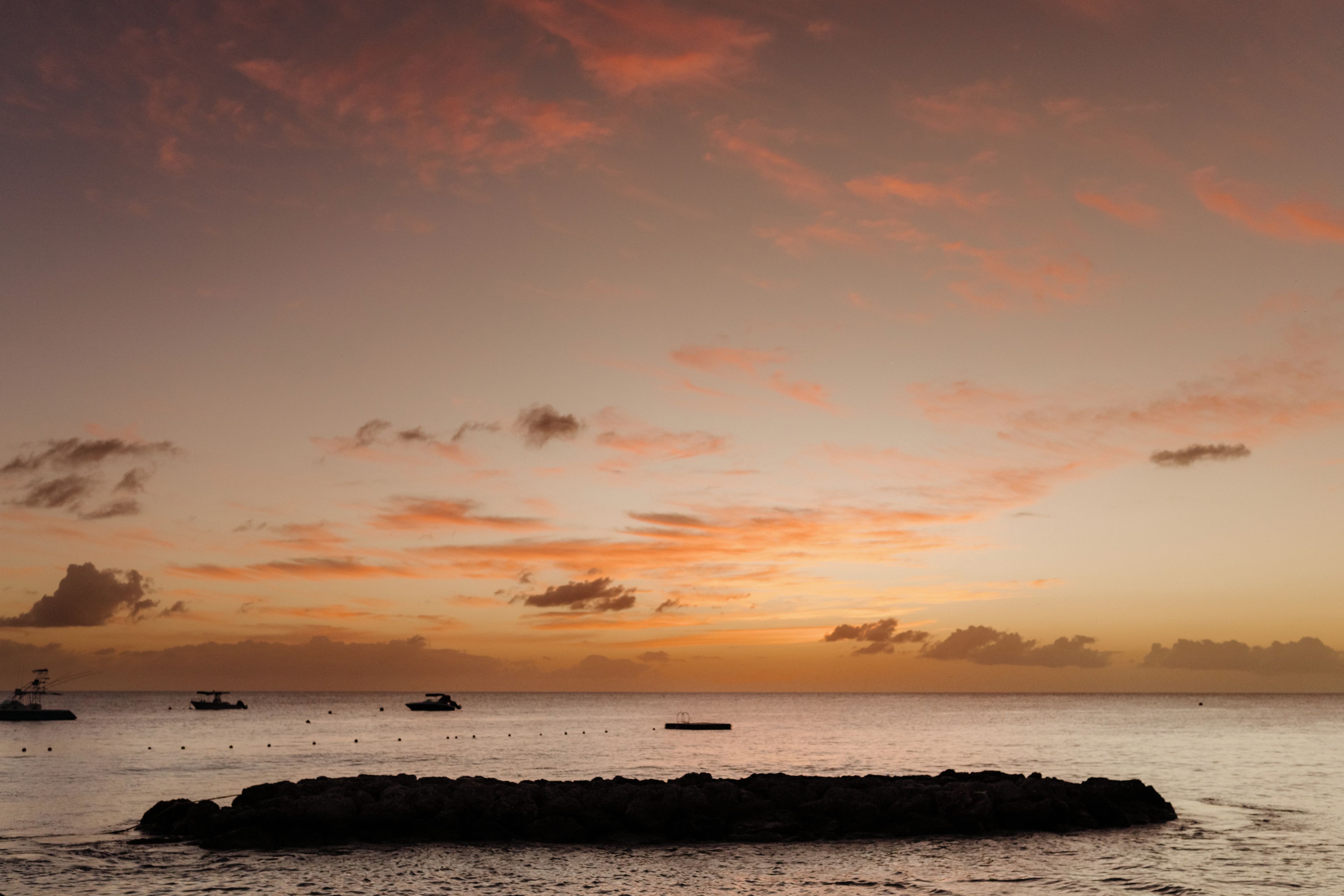 A coastal scene with a rocky outcrop in the foreground and a calm sea.