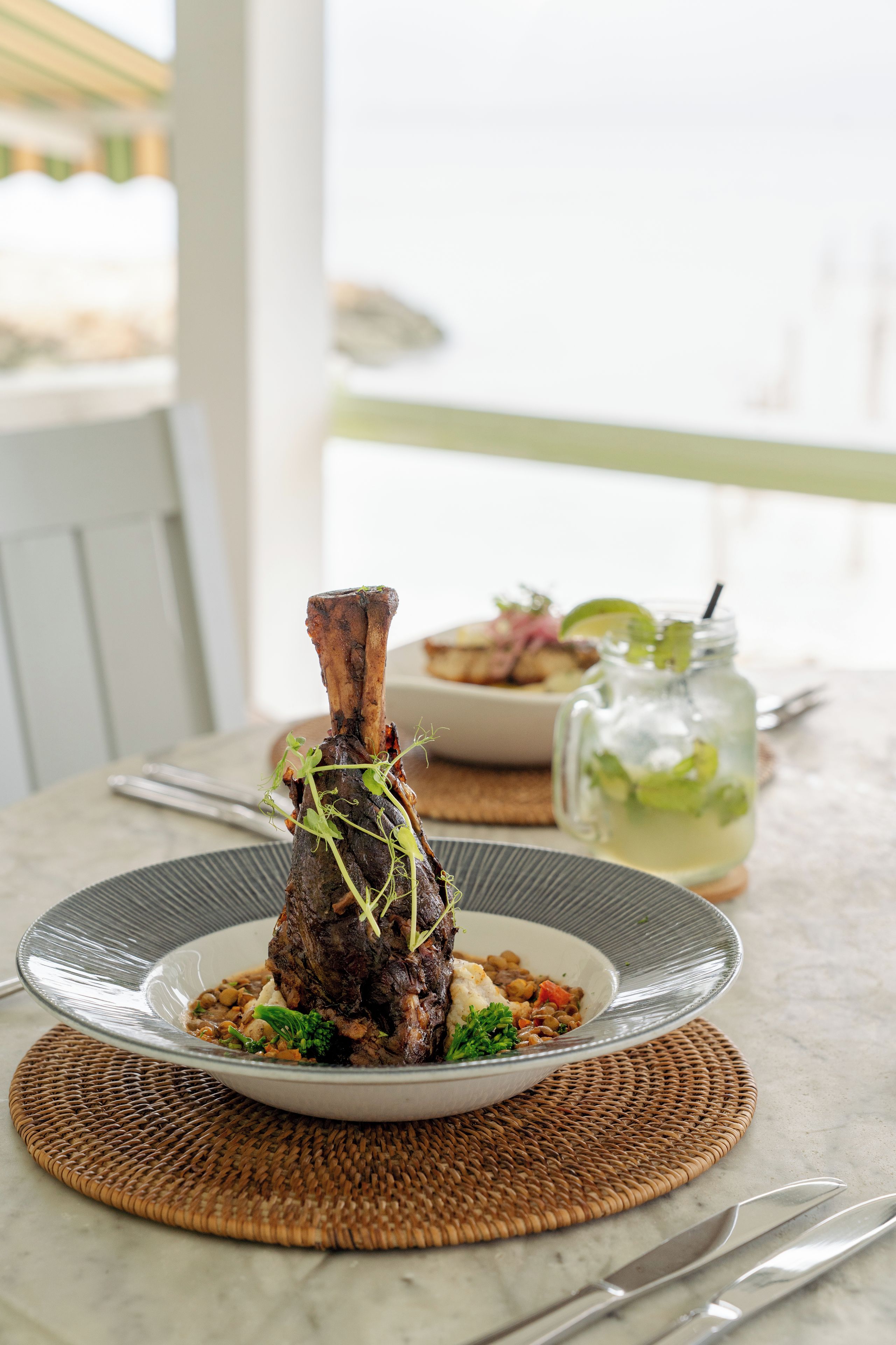 A dining table with a plate of food, a glass jar, and a fork.