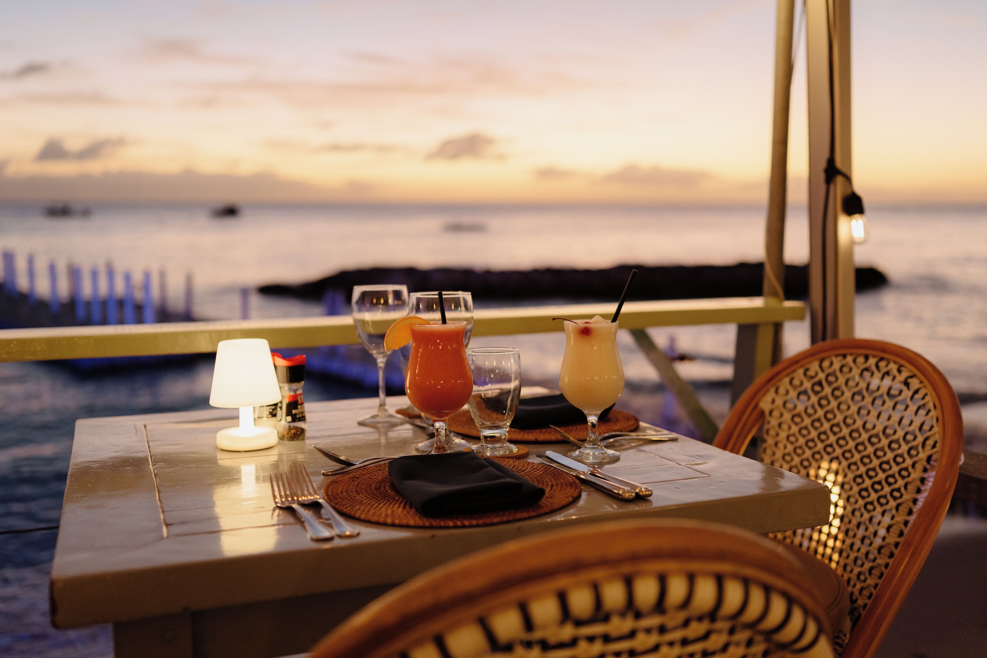 A table set for dining with a view of the sea at sunset.