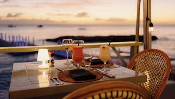 A table set for dining with a view of the sea at sunset.