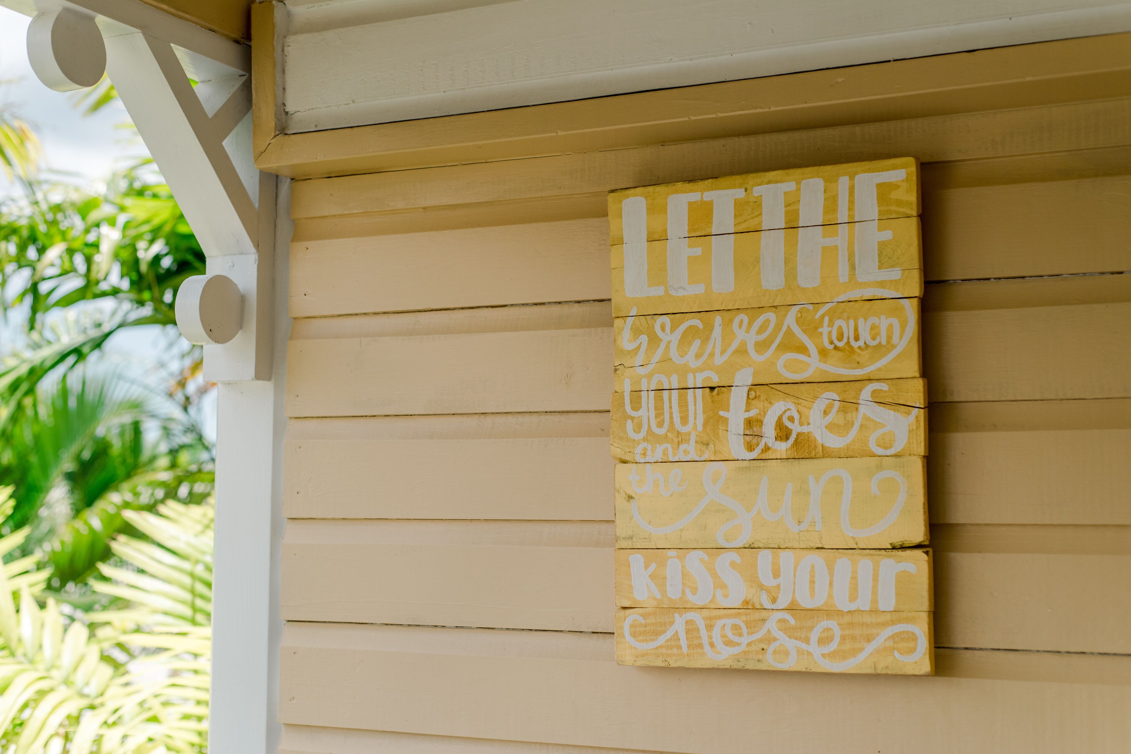 Un letrero de madera con el mensaje "LET THE GRAVEST TOUCH YOUR KISS YOUR NOSE" sujeto a un edificio.
