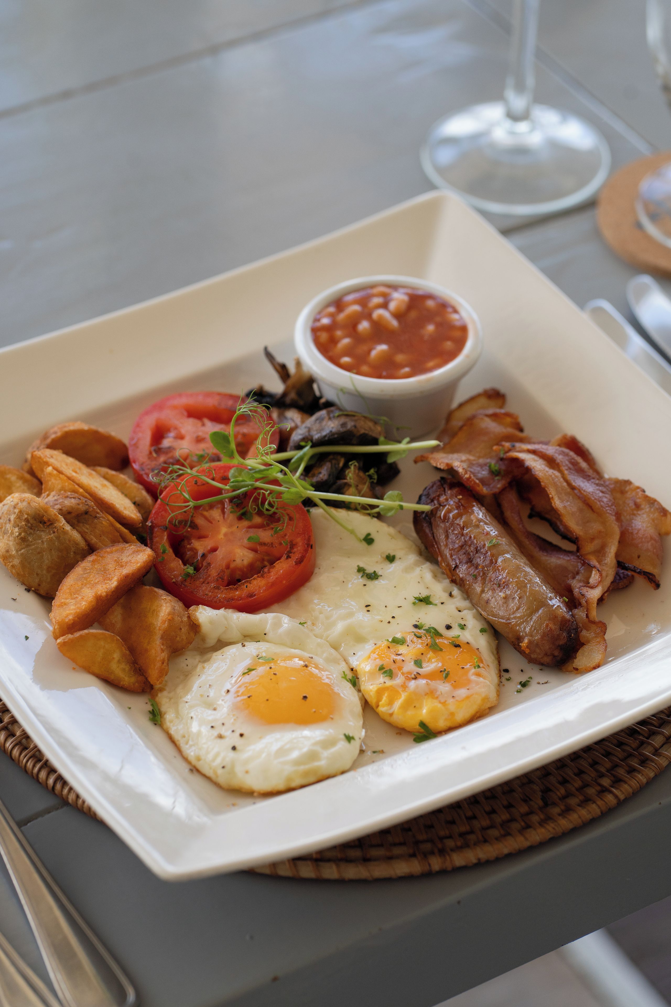 A breakfast plate with eggs, bacon, tomatoes, beans, and toast.