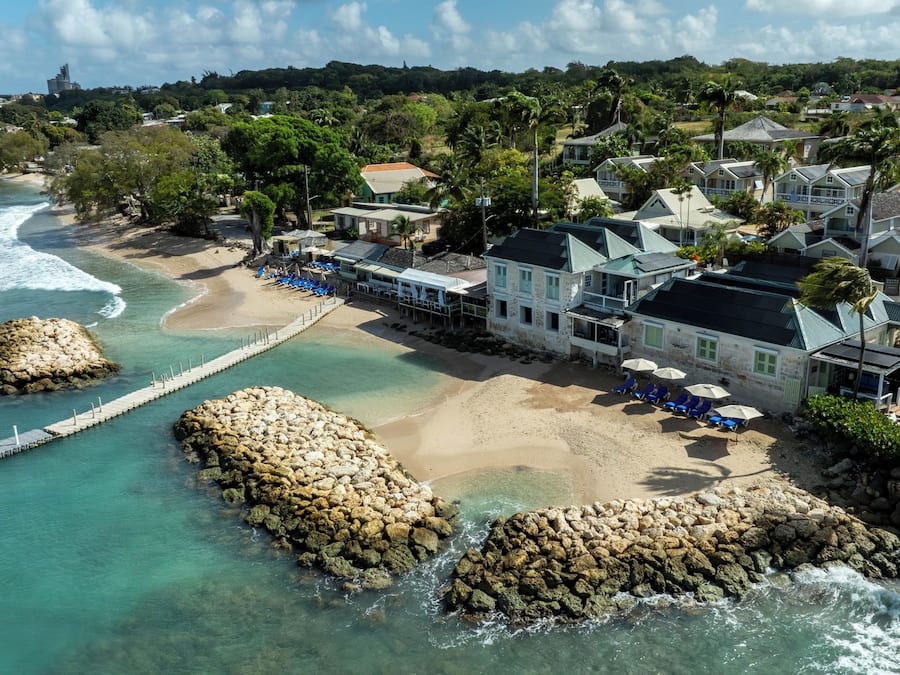 Un hotel sulla costa con spiaggia, vista sull'oceano e formazioni rocciose.