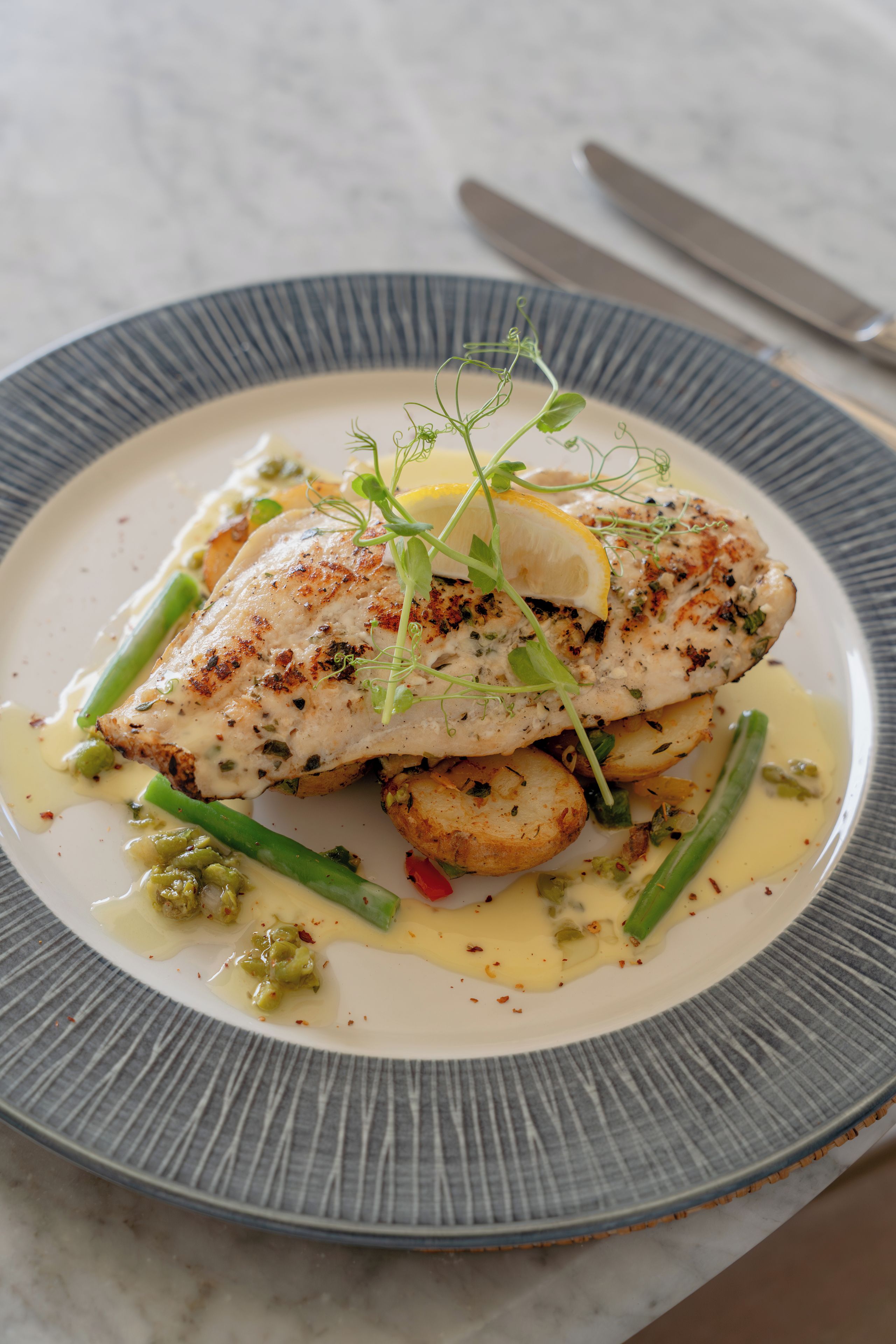Un plato de comida con un filete de pescado, judías verdes y patatas.