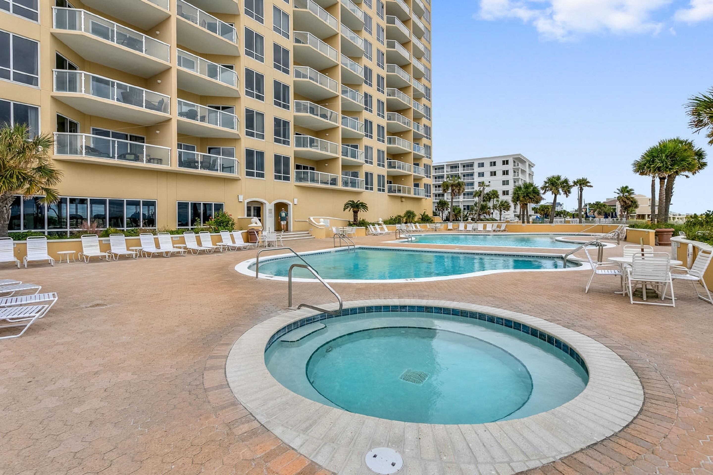 A hotel with a pool area featuring lounge chairs and a circular hot tub.