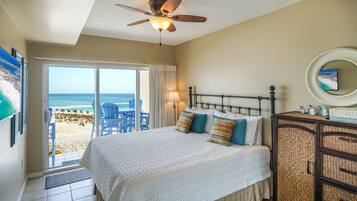 Ein Schlafzimmer mit Bett, Deckenventilator, Nachttisch und Blick auf den Strand.