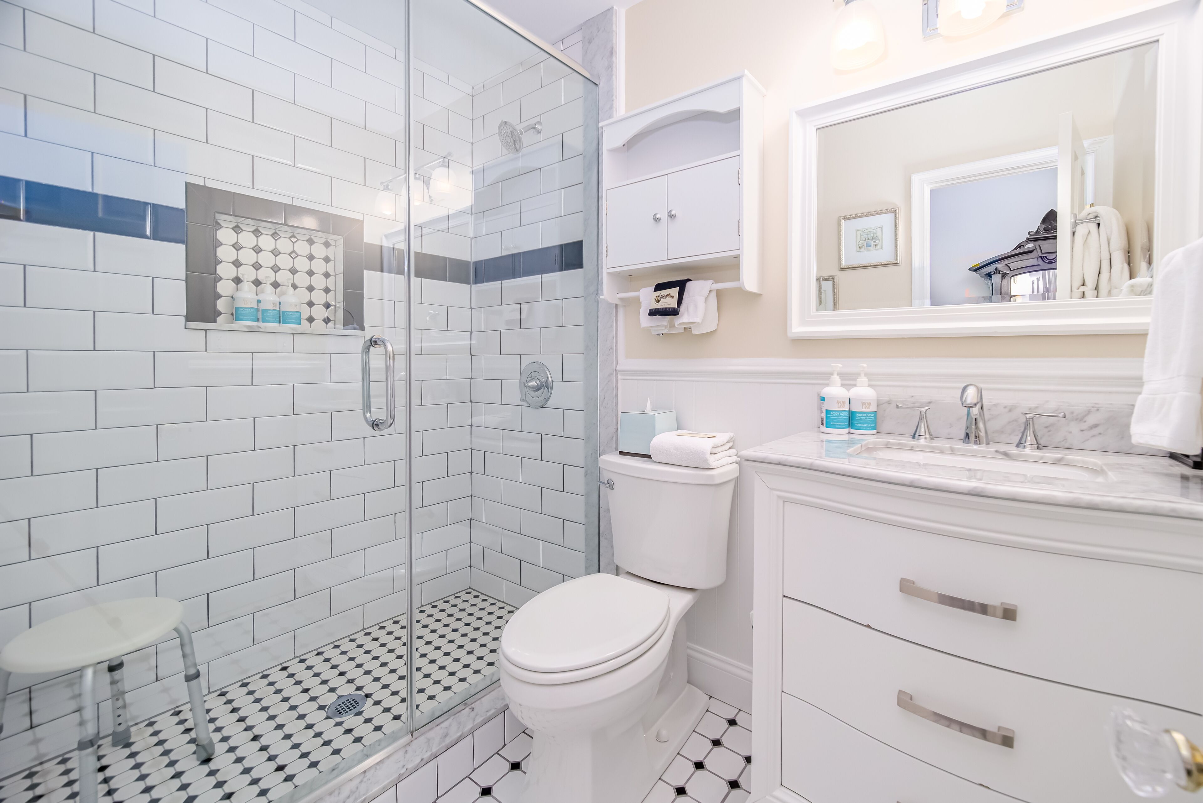 A modern bathroom with a glass-enclosed shower, a white toilet, and a vanity with a mirror.