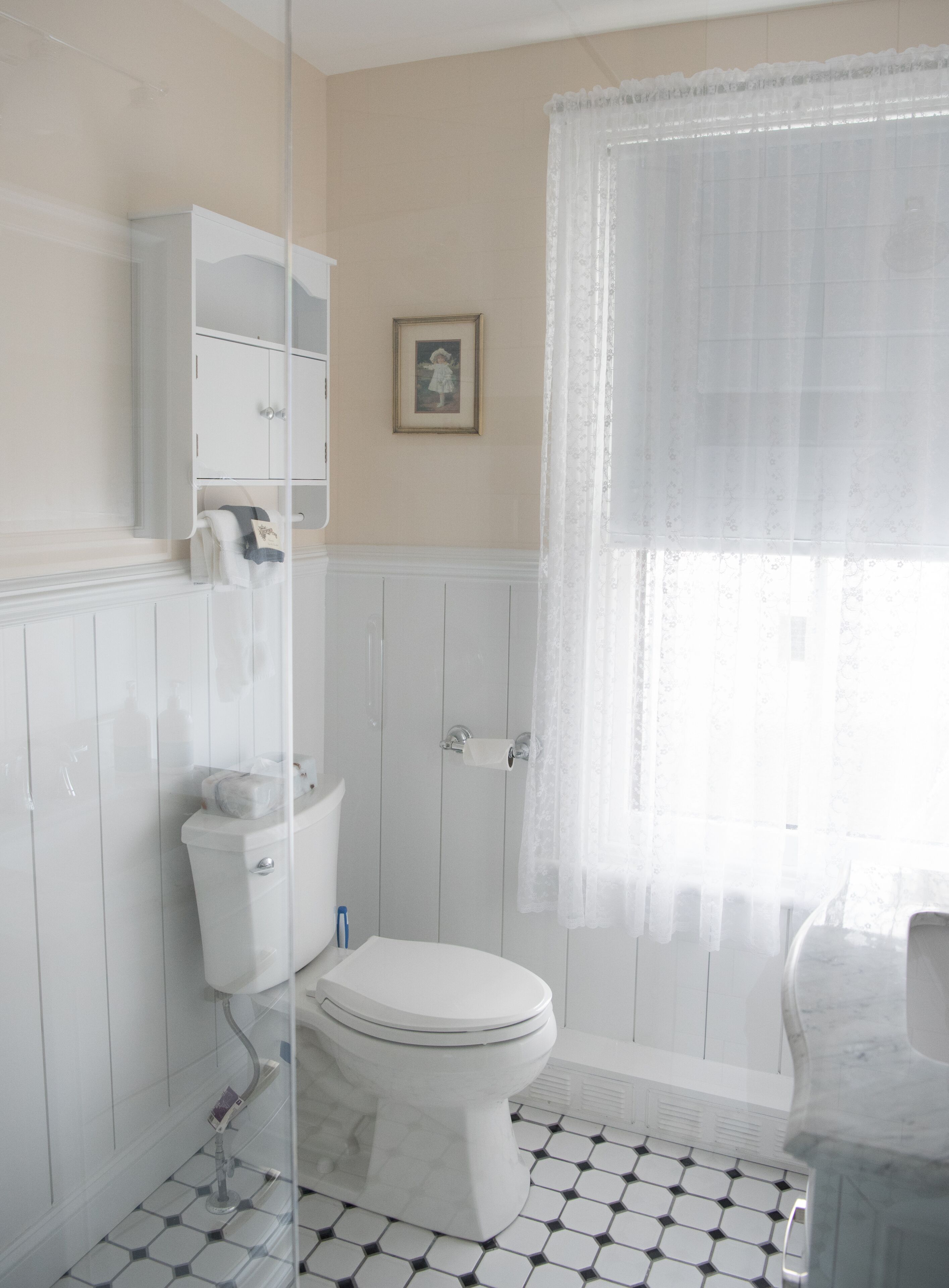 A bathroom with a toilet, a sink, a shower, and a cabinet.
