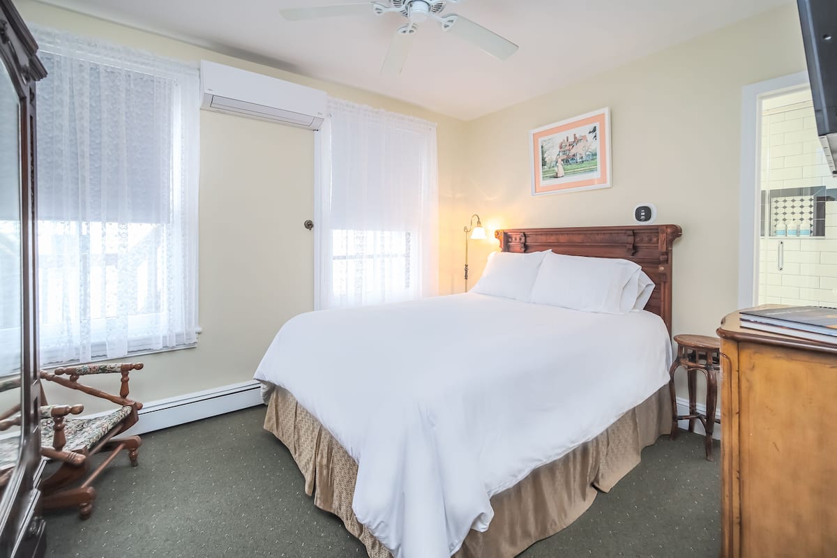 A bedroom with a large bed, a wooden headboard, a standing lamp, and a small wooden table.