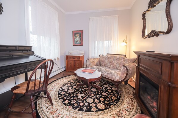 Uma sala de estar com um piano, um sofá, uma mesa de centro, uma lareira e um tapete estampado.