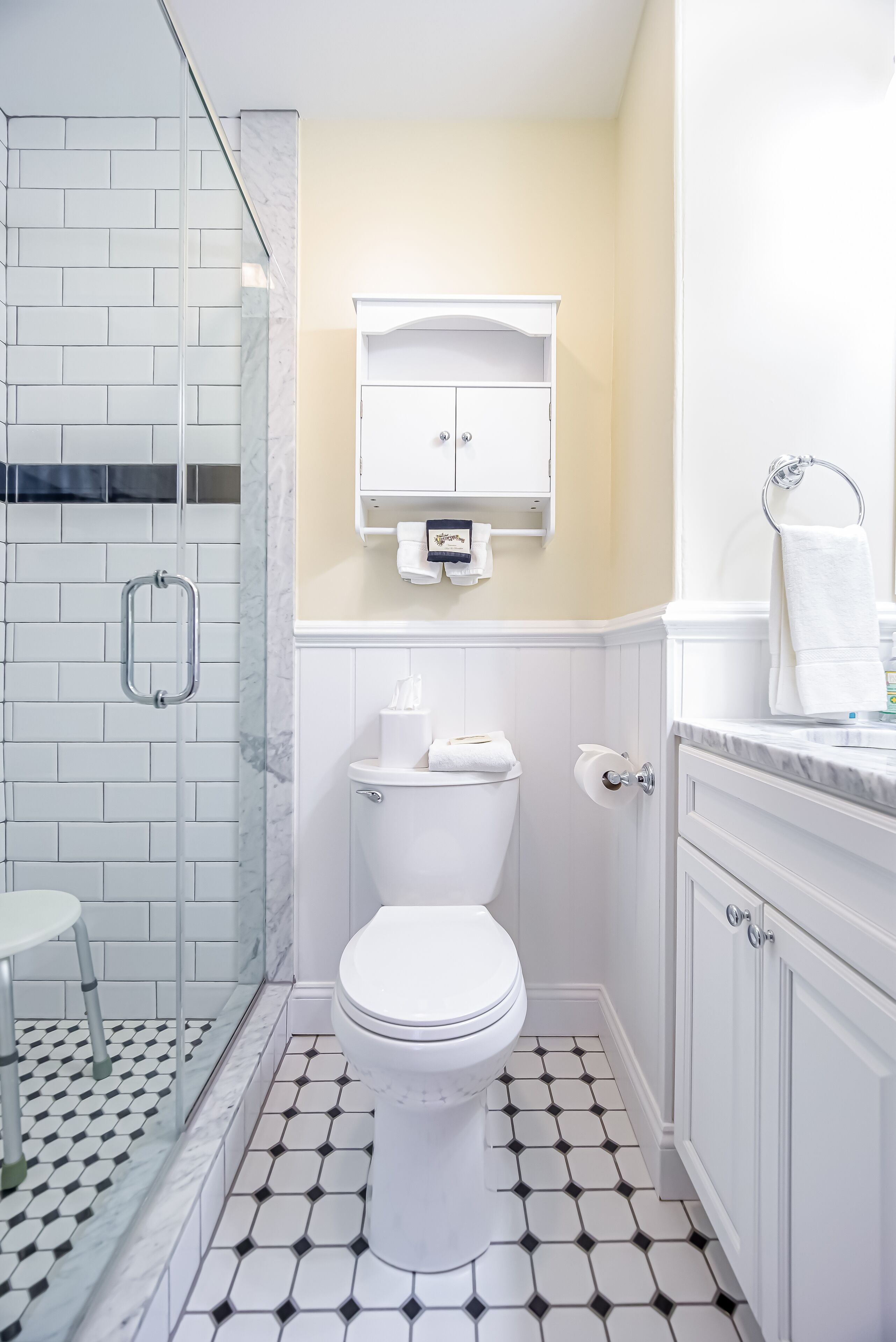 A bathroom with a white toilet, a glass shower enclosure, and a tiled floor.