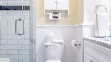 A bathroom with a white toilet, a glass shower enclosure, and a tiled floor.