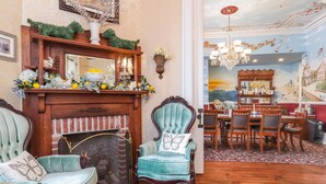 A cozy room with a fireplace, a dining area, and a mural of a seaside scene. - Bedford Inn (Cape May)
