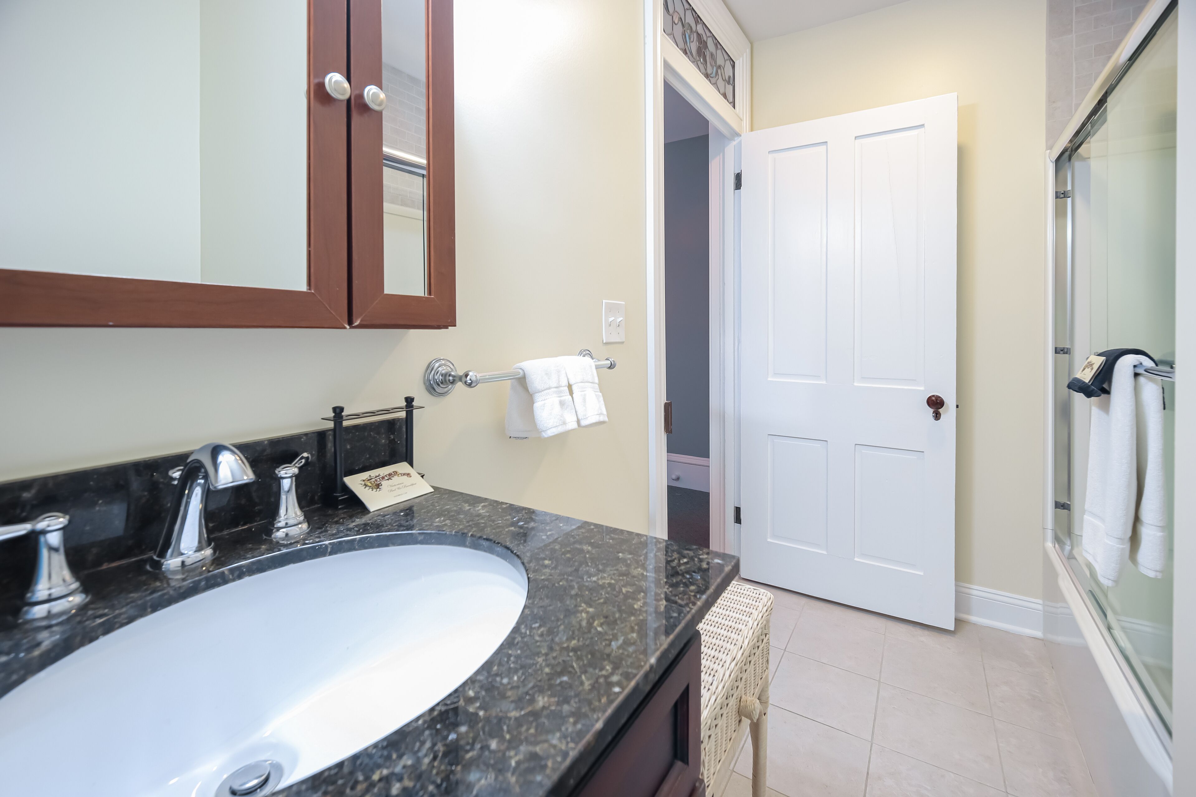 A bathroom with a large sink, a mirror, a towel rack, and a door leading to another room.