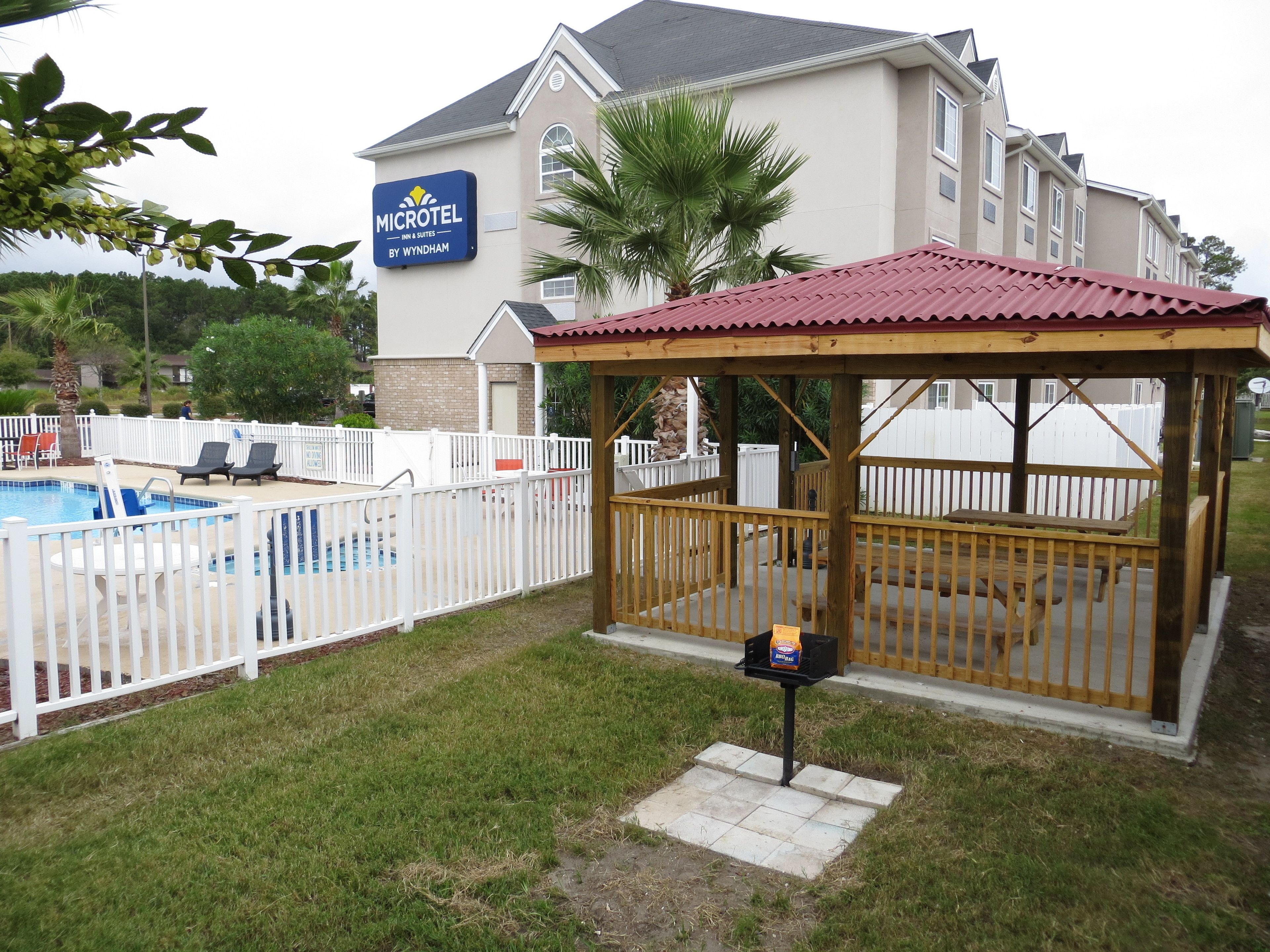A pool area with a fenced deck, lounge chairs, and a gazebo.