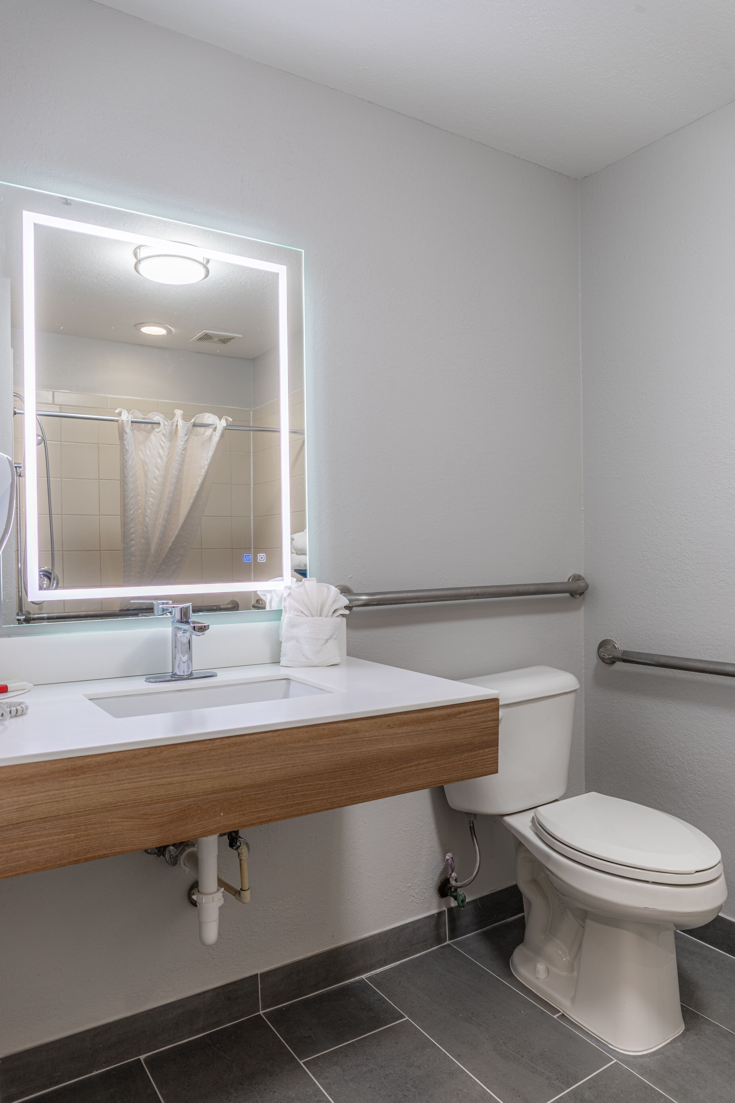 A modern bathroom with a white sink, mirror, and toilet.