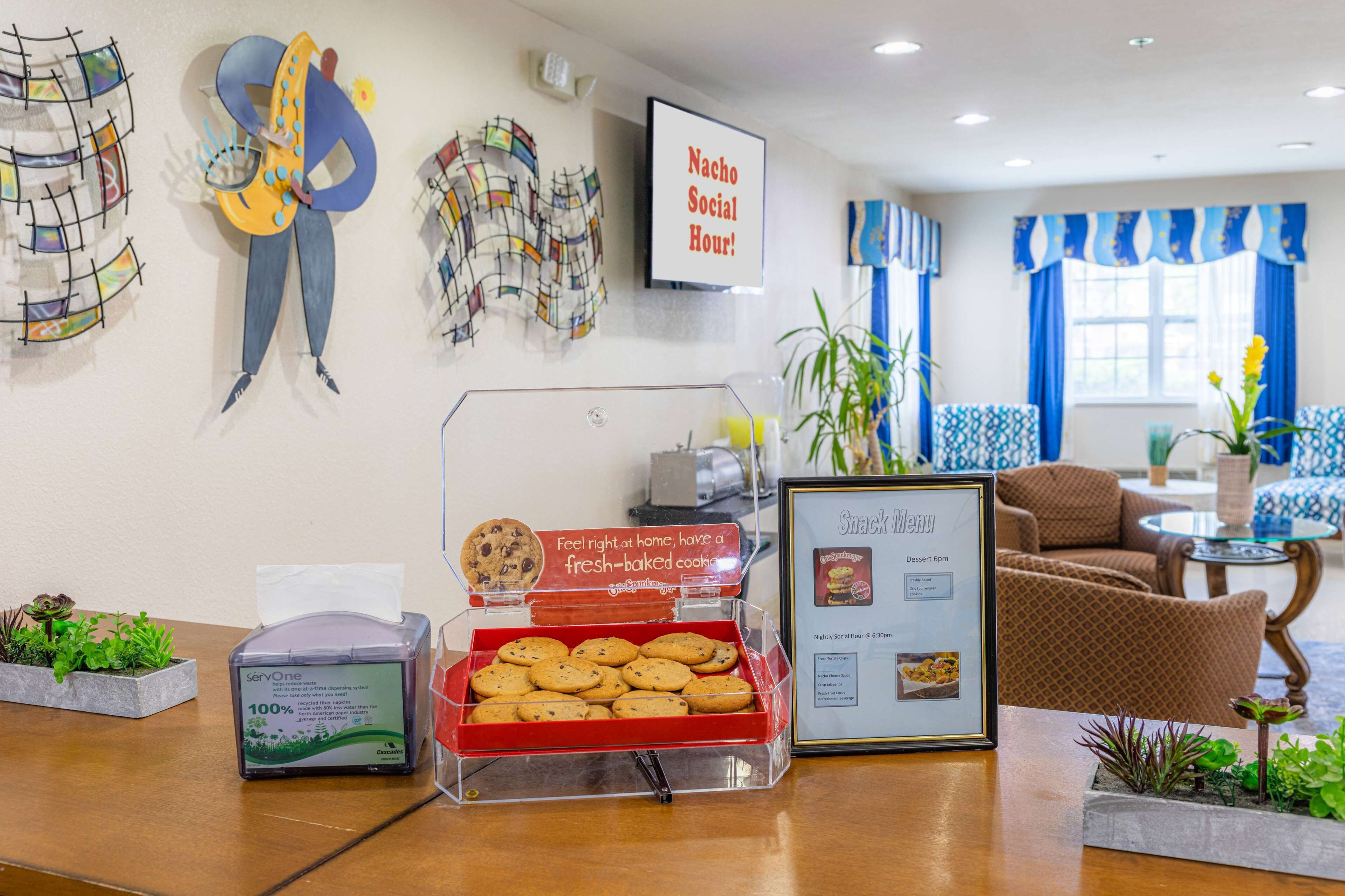 Un área de recepción con menú de aperitivos, una presentación de galletas y decoración en la pared.