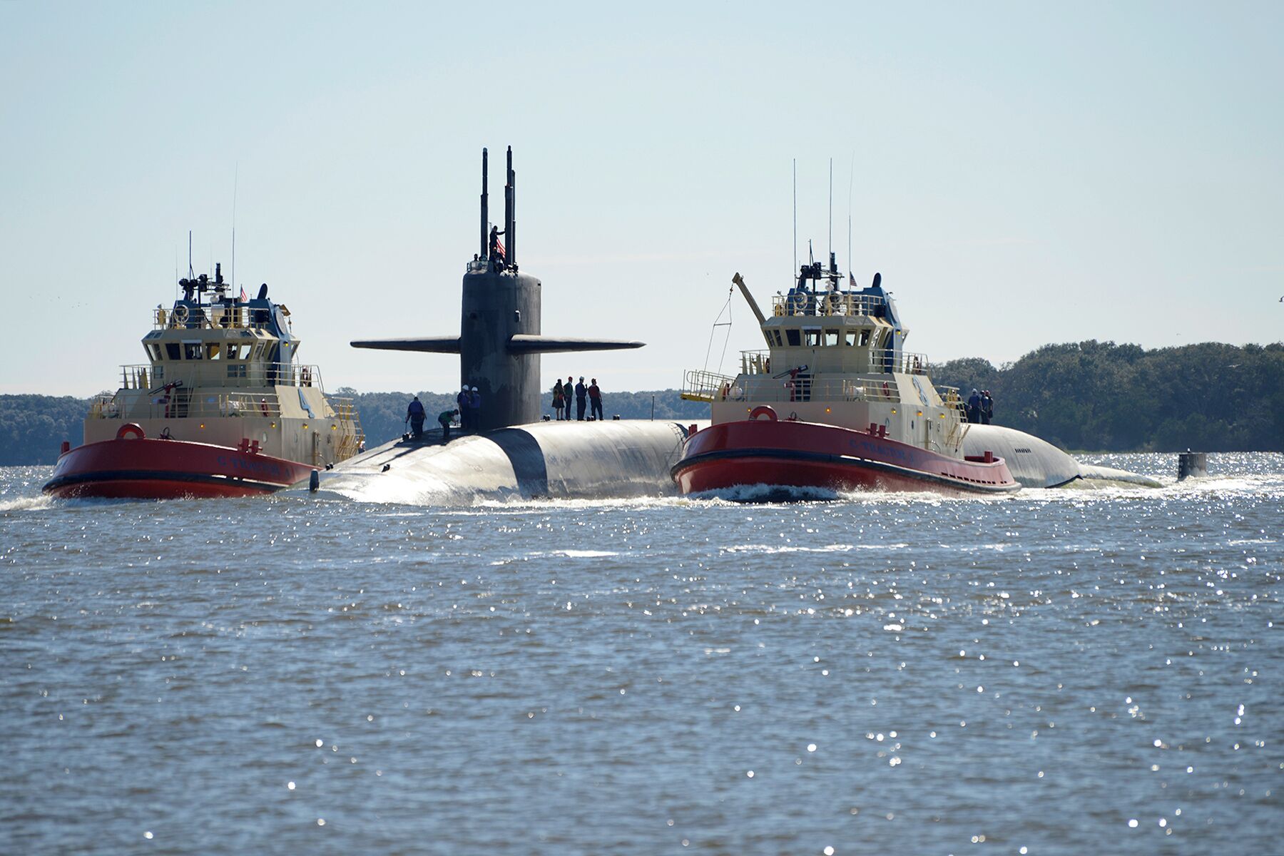 Dos grandes submarinos militares con tripulantes en cubierta, navegando sobre el agua.