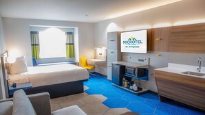 A hotel room with a bed, a desk, a chair, a TV, a microwave, a sink, and a minibar. - Microtel Inn & Suites by Wyndham Kingsland Naval Base I-95 (Kingsland)