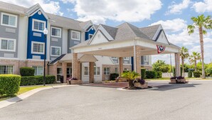 A multi-story hotel with a covered entrance and a flag. - Microtel Inn & Suites by Wyndham Kingsland Naval Base I-95 (Kingsland)