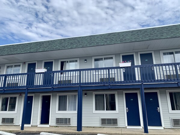 A row of white motel rooms with blue doors and windows, a covered balcony, and a green roof. - Sunbird ANNEX Resort (West Yarmouth)