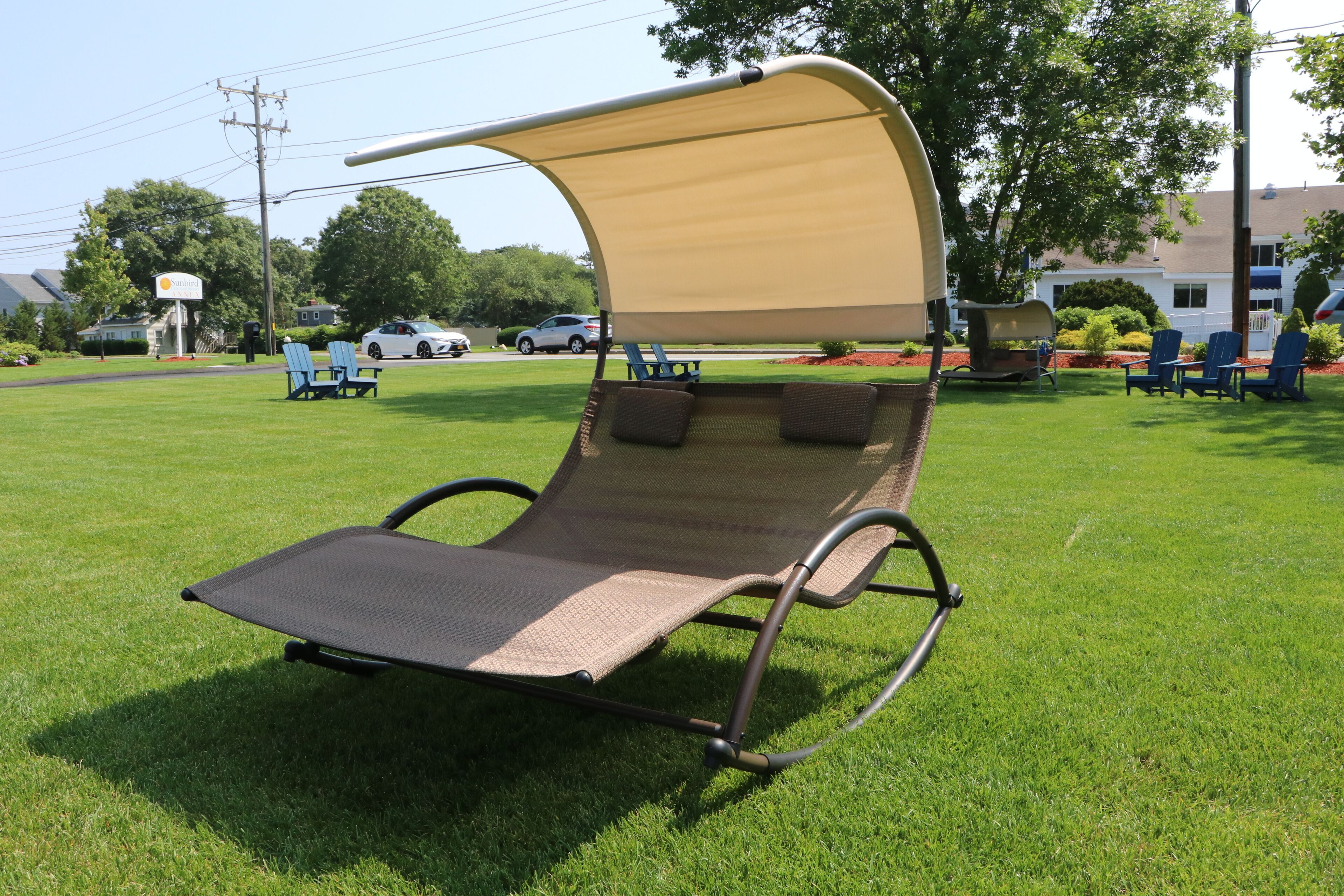 A sun lounger with a canopy, positioned on a grassy lawn.