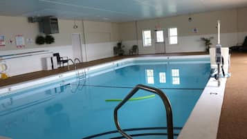 An indoor swimming pool with clear water, marked depth lines, and a lifeguard chair.