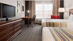 A hotel room with a bed, a desk with a television, a chair, a dresser, and a window with curtains. - Country Inn & Suites by Radisson, Appleton North, WI (Little Chute)