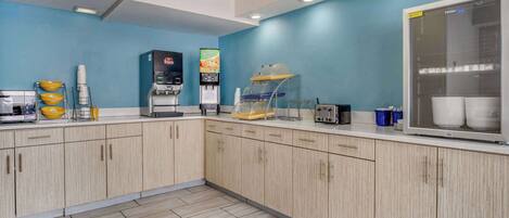 A modern kitchen with light wood cabinets, a blue wall, and a large refrigerator.